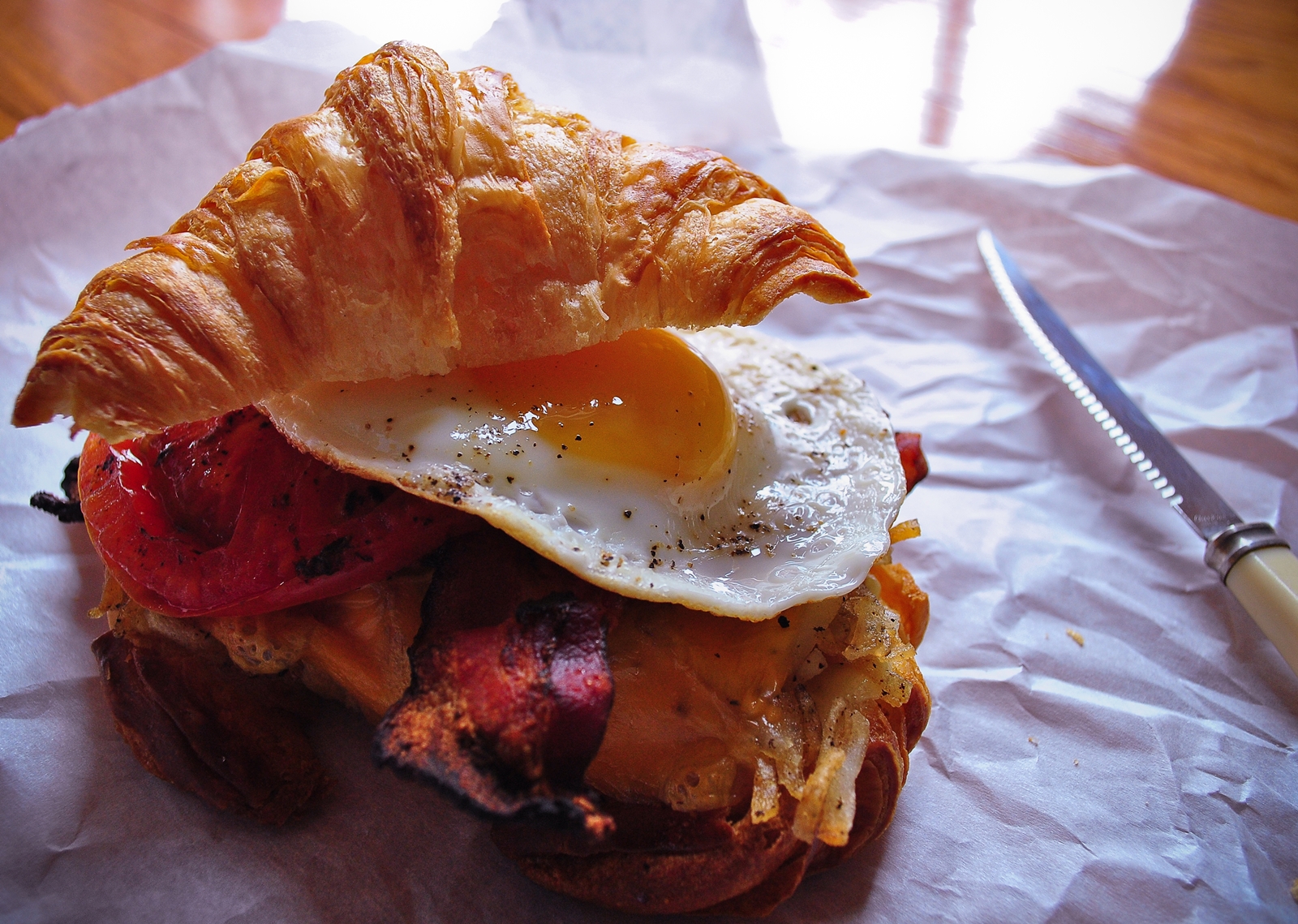 Fluffy croissant breakfast sandwich with crispy bacon, fried egg and hash browns